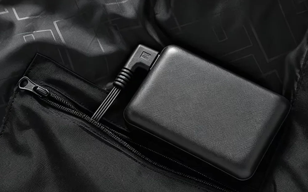 Power bank tucked into the inside zip pocket, plugged into the jacket's USB cable