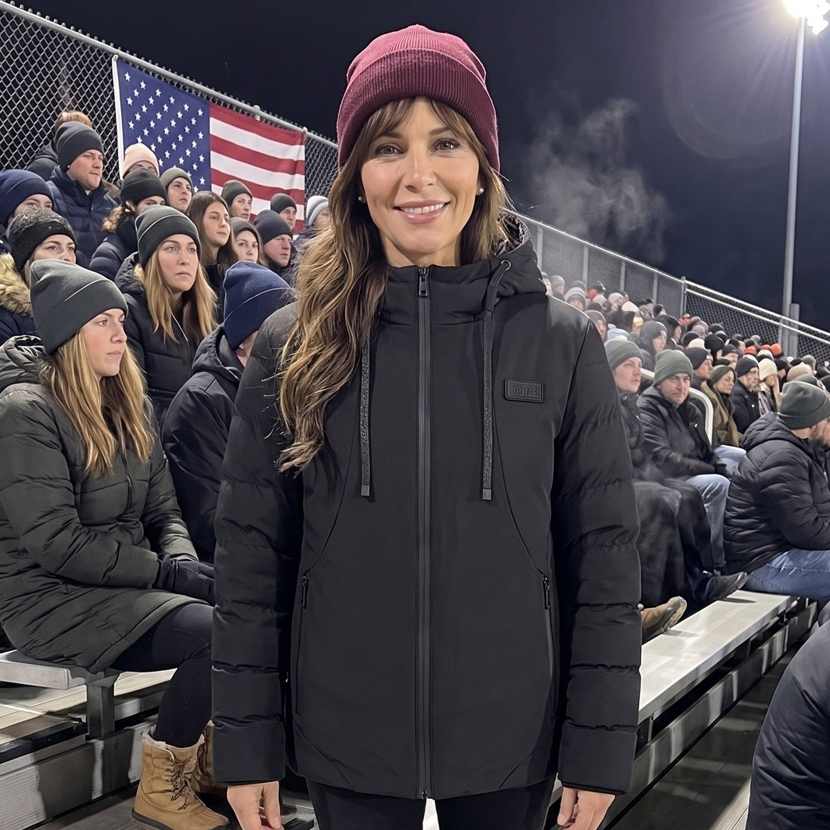 Woman wearing the black heated hooded jacket at a cold night football game
